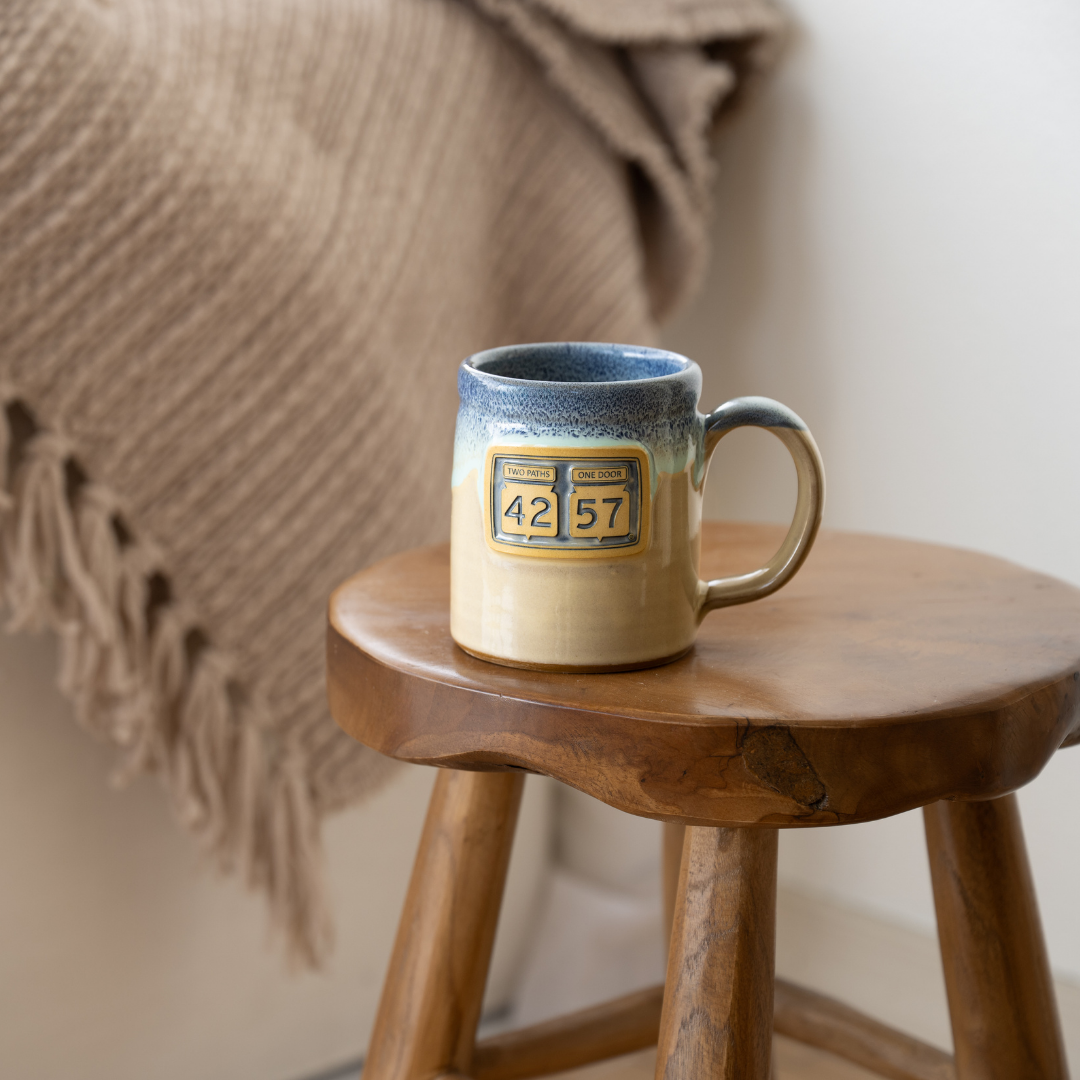 42-57 Gallery Mug in beige styled on wooden stool