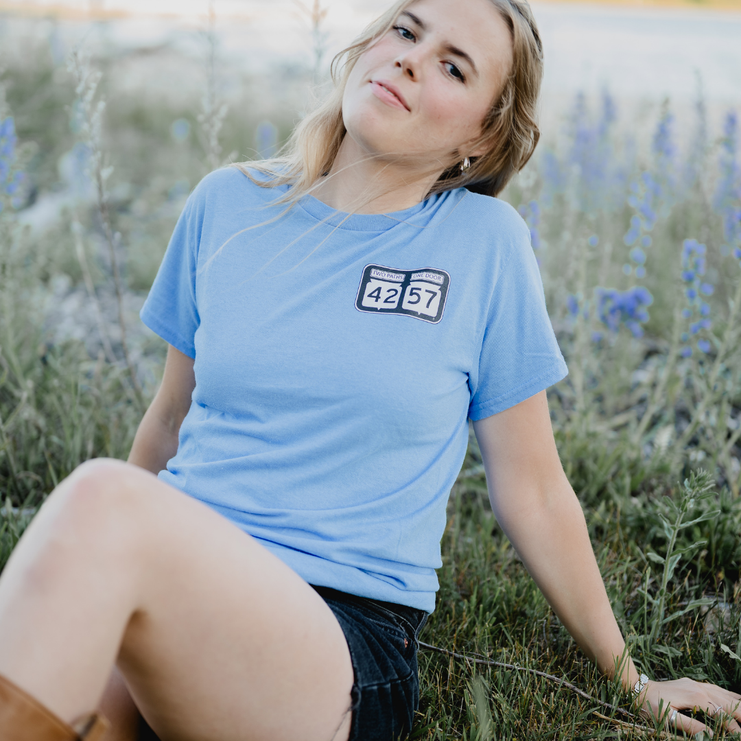 Model wearing 42-57 Women’s Classic Tee in light blue in a Door County setting
