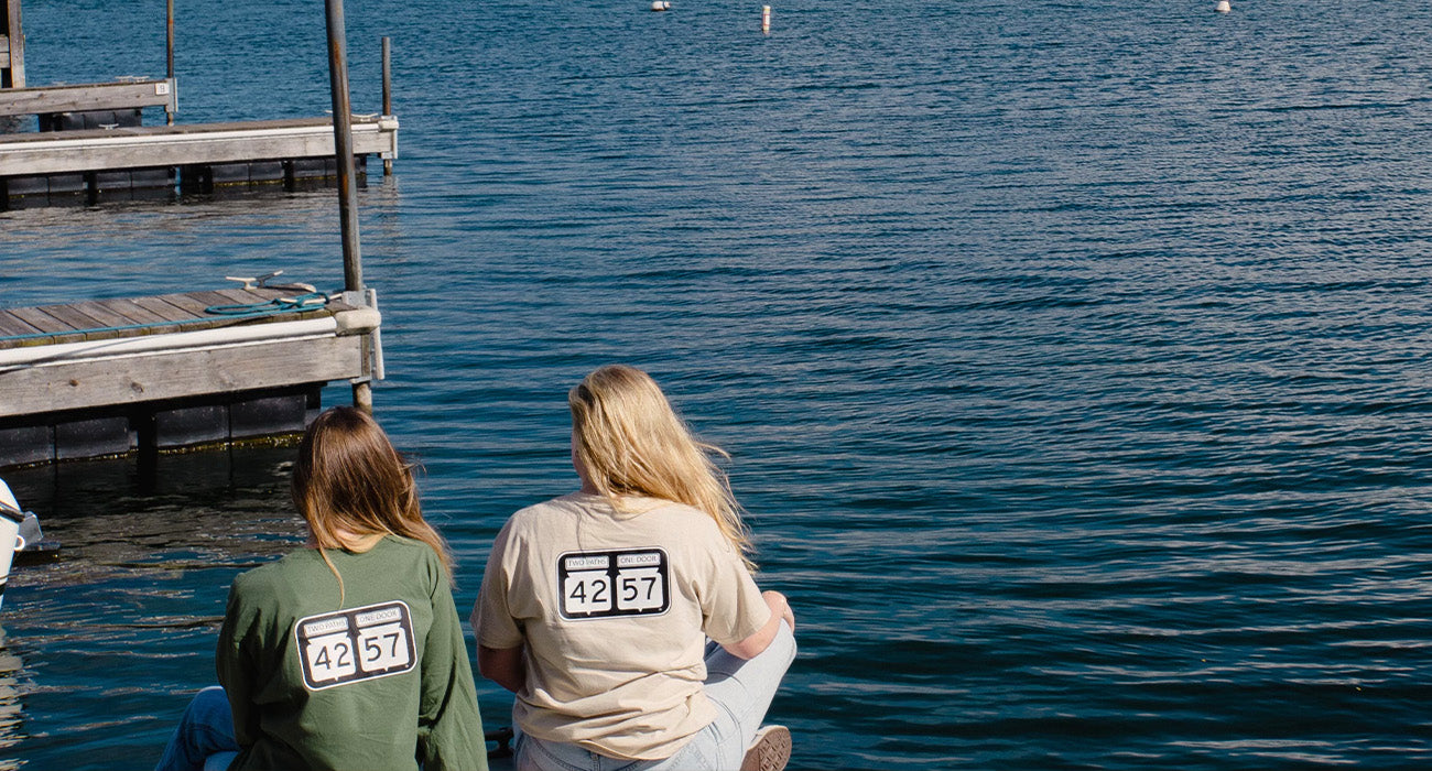 two girls sitting on a dock in 42-57 shirts